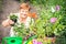 Gardener active senior elderly woman is holding the pot of flower in the garden.