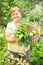 Gardener active senior woman is holding basket of freshly picke