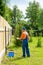 Gardener in blue uniform paints new wooden fence