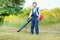 Gardener clearing up the leaves using a leaf blower