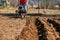 Gardener cultivate ground soil with tiller tractor or rototiller, cutivator