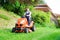 Gardener driving a riding lawn mower in garden