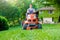 Gardener driving a riding lawn mower in garden