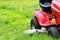 Gardener driving a riding lawn mower in a garden . Cutting grass