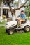 Gardener driving a riding lawn mower in home garden