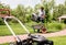 Gardener emptying lawn mower grass into a wheelbarrow after mowing.
