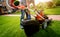 Gardener emptying lawn mower grass into a wheelbarrow after mowing.