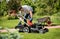 Gardener emptying lawn mower grass into a wheelbarrow after mowing.