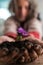 Gardener holding a purple flower cupped in his hand in soil