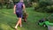 Gardener man pushing wheelbarrow with cut grass for compost. Little girl