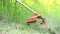 Gardener mowing grass by brush cutter in garden close up