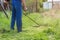 The gardener mows the grass with a trimmer in the spring garden