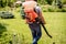 Gardener in protective mask and glasses spraying toxic pesticides trees