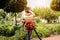 Gardener in protective mask and glasses spraying toxic pesticides trees