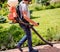 Gardener in protective mask and glasses spraying toxic pesticides trees