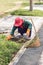 Gardener pulling out weeds in public park in Thailand, motion bl