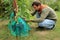 Gardener sits and covers blue grape bunches in protective bags t