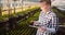 Gardener using digital tablet in greenhouse