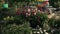 A gardener is watering flowers on a warm sunny day, water spraying onto fresh flower bushes.