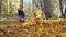 Gardener woman with girl playing with leaf blower and colorful autumn leaves