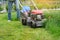 Gardener woman legs mowing grass with lawnmower, city courtyard of an apartment building