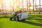 Gardener worker on lawn mower tractor cuts green grass