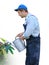 Gardener - worker in working clothes, watering plants with watering can