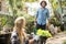 Gardener working while female coworker holding plants