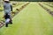 Gardener working on the lawn in a cemetery with headstones in the background