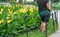 Gardener working in public park with gloves in her pocket. Unrecognizable Person Green farmer uniform with flowers in botanical