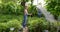 Gardeners man and woman standing together and spraying water on flowers