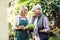 Gardeners standing with potted plant and clipboard