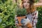 Gardening concept. Young woman holds potted lavender plant outdoors.