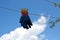 Gardening gloves hang on a rope against the blue sky.