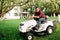 Gardening, grass trimming in progress. Male worker using lawnmower and smiling