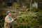 Gardening and people concept - happy senior woman watering lawn by garden hose at summer