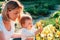 Gardening. Portrait of a caucasian mother and her little child touching yellow iris flowers. Sunny sunset. Summer garden