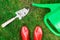 Gardening tools, red garden shoes, small spade, watering can on the grass, close up.