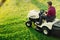 Gardening with young male cutting grass. Industrial lawn mower in action