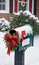 Garland Wrapped Around A Mailbox Stuffed With Christmas Cards, Afternoon, Snowing, Shot From The Front. Generative AI