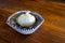 A garlic bulb in a decorative bowl on a wooden table.