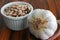 Garlic bulbs. Closeup of a garlic on wooden spoon. Ramekin with pinto beans in the background. Selective focus. Wooden table.