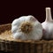 Garlic bulbs in a wicker basket front view with brown background