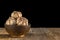 Garlic in dark bowl on wooden table. Isolated on black