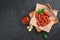 Garlic Mani sausages with sauce in a wooden plate on a black background.