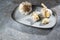 Garlic on a plate and a grey stone background, the healthy cloves lower blood pressure and inhibit bacteria and fungi, copy space