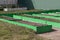 Garlic and vegetable crop in green plastic frames. Raised beds in garden box in early spring. Herbs growing in container