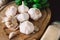 Garlic on a wooden board on a black background, with dried garlic and a bunch of basil. Condiments and spices.