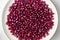 Garnet fruit seeds on the round plate on white background top view. Pomegranate seeds natural background.