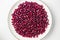 Garnet fruit seeds on the round plate on white background top view. Pomegranate seeds natural background.